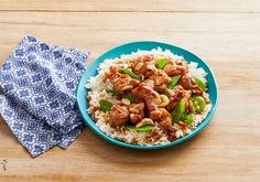 a blue plate topped with rice covered in meat and veggies next to a napkin