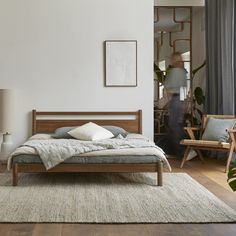 a bed sitting on top of a wooden floor next to a chair and table in a room