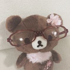 a brown teddy bear wearing glasses on top of a white blanket with a pink flower in it's hair