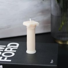 a white candle sitting on top of a book