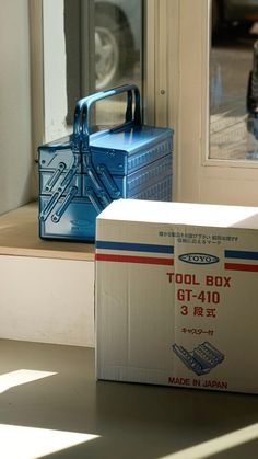 a tool box sitting on top of a window sill next to a blue container