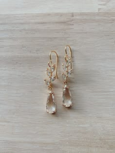 two pairs of gold tone earrings with clear crystal drops on wooden background, closeup