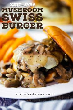 a mushroom swiss burger on a plate with french fries and carrots in the background