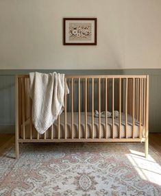 a baby crib with a blanket on top of it in front of a wall