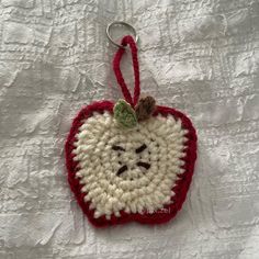 a crocheted apple ornament hanging on a white sheet