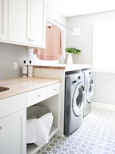 a washer and dryer in a white laundry room with light wood counter tops