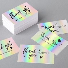 thank you cards with rainbow holographics and black ink on them are shown