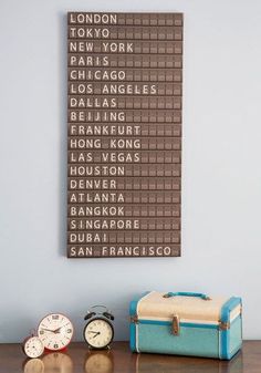 there is a luggage bag and two clocks on the table in front of a sign