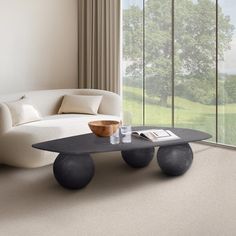 a living room with a couch, coffee table and large window looking out onto the countryside