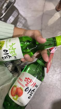 a person holding two bottles of water in their hands, one is green and the other is red