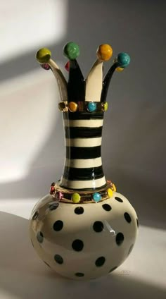 a black and white striped vase with lots of colorful beads on it's sides