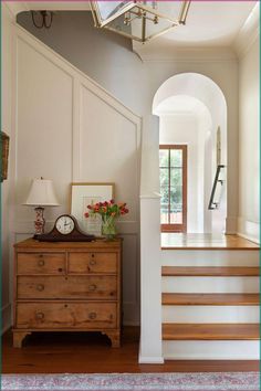 a wooden dresser sitting under a doorway next to a stair case with flowers on it