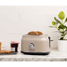 a toaster sitting on top of a white counter next to a potted plant