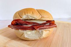 a bacon and cheese sandwich sitting on top of a wooden cutting board