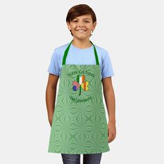 a young boy wearing an apron with the irish flag on it, smiling at the camera