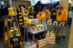 a store display filled with yellow and black shirts, backpacks and stuffed animals on wooden crates