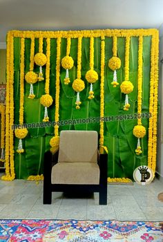 a chair sitting in front of a green wall decorated with yellow pom poms