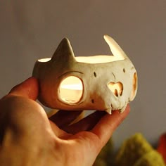 a person holding a cat shaped object with its eyes glowing in the light from behind