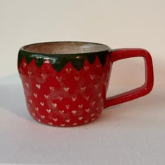 a red and black coffee cup with hearts on the inside is sitting on a white surface