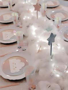 a table set for a baby shower with white and pink plates, napkins and silverware