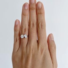 a woman's hand with a diamond ring on her left and the middle finger