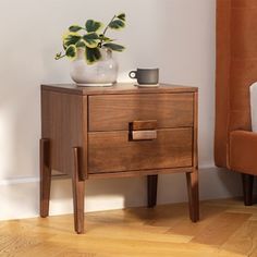 a small wooden table with two drawers and a cup on it next to a chair