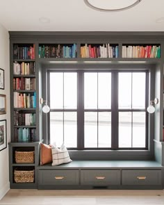 a window seat in front of a book shelf filled with books