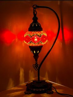 a lamp that is sitting on top of a table next to a red light in the background