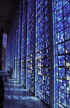 the inside of a building with many blue glass windows on each wall and stairs leading up to it