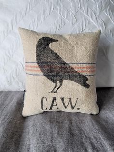 a black bird sitting on top of a pillow with the word caw printed on it