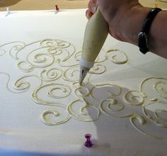 someone is using a pen to draw swirls on the fabric with white paper and glue