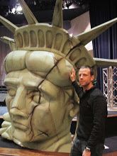 a man standing in front of a statue of liberty's head on display at a museum