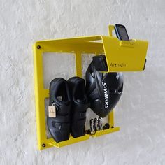 a pair of black shoes hanging on a yellow shelf with a cell phone in it