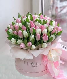 a bouquet of pink and white tulips sitting on top of a counter next to a window