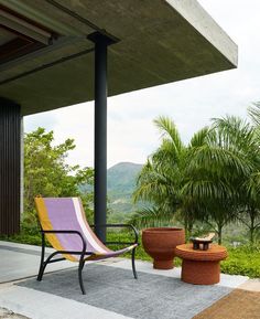 a chair and table on a patio with mountains in the background