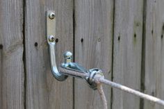 a close up of a metal hook on a wooden fence with rope attached to it