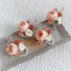 three pink and white flowers sitting on top of a gray tray with a name tag