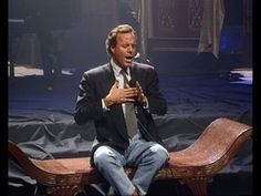 a man in a suit and tie sitting on a bench with his hands folded open