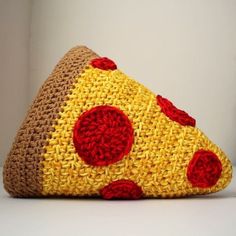 a crocheted purse with a slice of pizza on it's side, sitting on a white surface