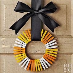 a wreath made out of matchesticks is hanging on a door with a black bow