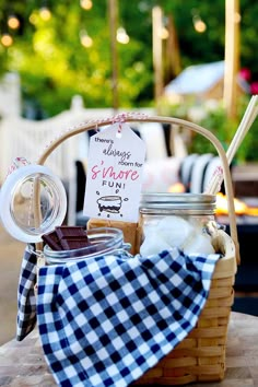 a picnic basket filled with cookies and other items on top of a wooden table next to a sign that says diy s'mores gift basket