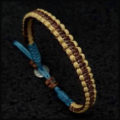 a braided leather bracelet with gold and blue beads on black background, close up