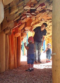 a man and two children are standing in a tunnel made out of wood planks