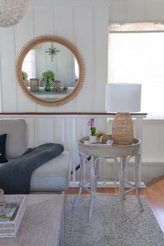 a living room filled with furniture and a round mirror on the wall above a table