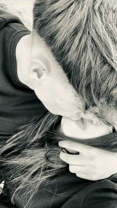 a woman with long hair is kissing the forehead of a man in black and white