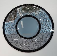 a round mirror with black and white mosaic design on the bottom, hanging from a wall