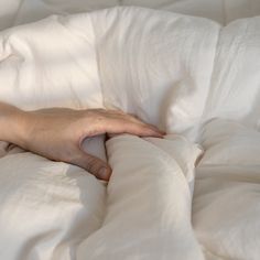 a person's hand on top of a white comforter