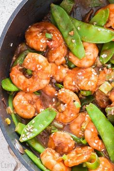 shrimp, snow peas and snap peas in a skillet with sesame seeds on the side