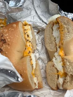 two sandwiches with cheese and other toppings sitting on tin foil wrapped in aluminum foil