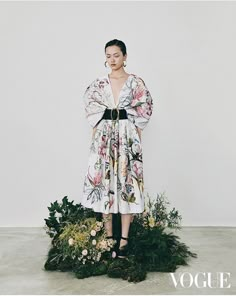 a woman standing on top of a lush green plant covered in white and pink flowers